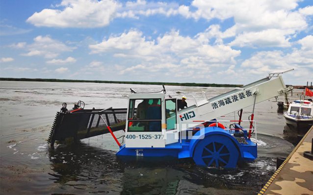 Малогабаритный комбайн для уборки сорняков на берегу водоема.